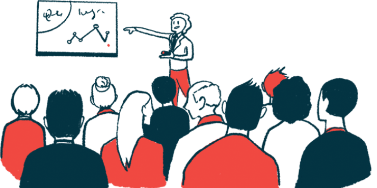 A person points to a chart on a wall while making a presentation in front of a crowd.